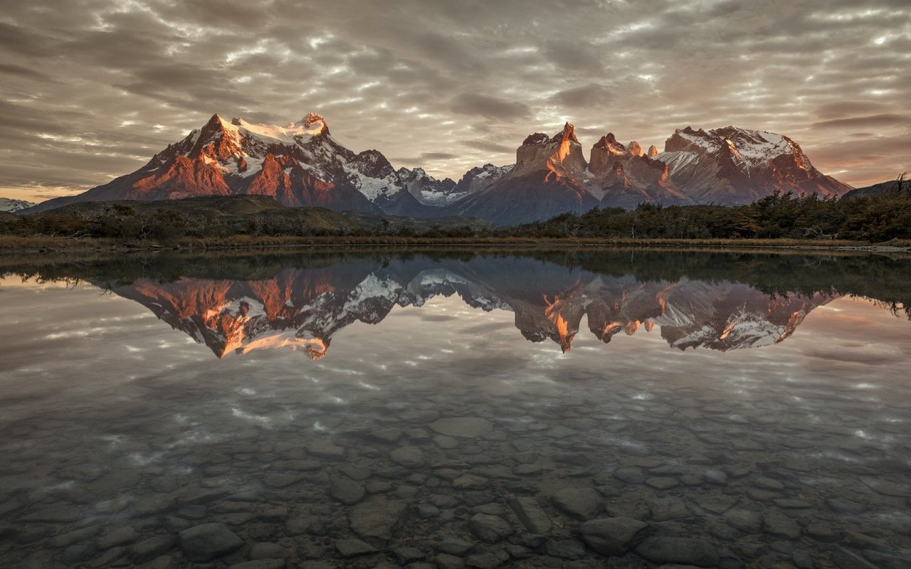 Das Paine-Massiv zeigt sich bei Sonnenaufgang in perfekter Spiegelung im Torres-del-Paine-Nationalpark.